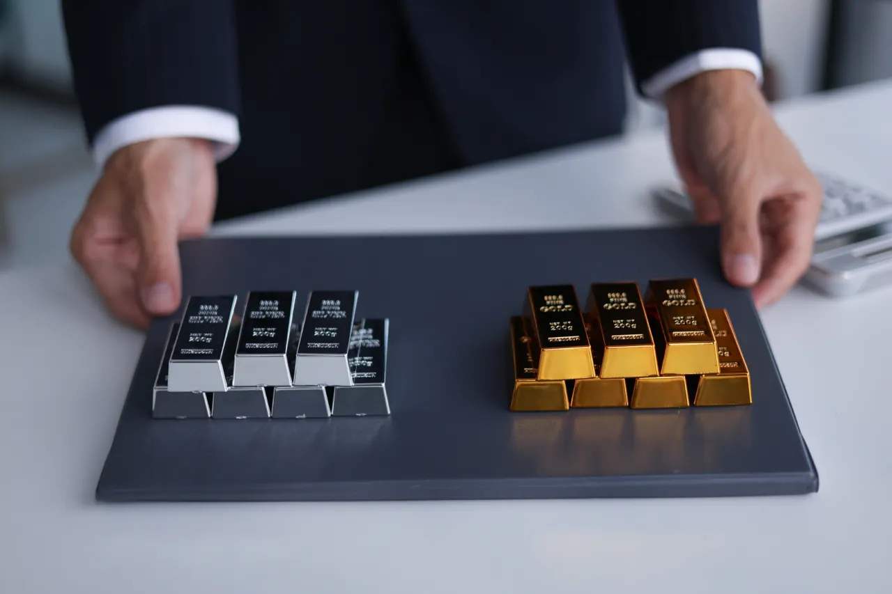 Gold- und Silberbarren auf einem Tisch vor einem Geschäftsmann